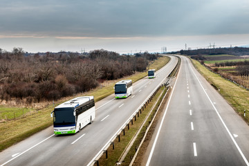 Three local line buses in line traveling on a highway country highway