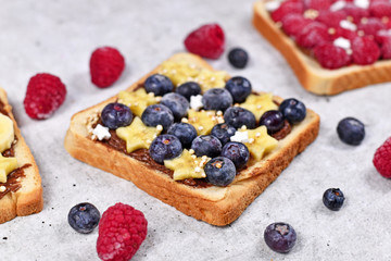 Slice of spelt toast bread topped with healthy blueberry and banana fruits and puffed quinoa grains