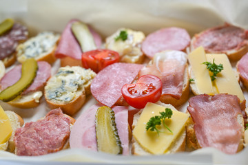 Various baguette canapes with cheese and sausage, tomatoes and gherkins on a casual party buffet