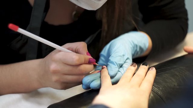 Manicurist varnish the client’s nails with a brush. Close-Up