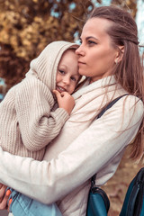 Fototapeta premium Woman mom holds in her arms little boy son, autumn day on walk in summer. Emotions care parenting support love. Happy baby smiling. Emotions comfort joy relaxation weekend.