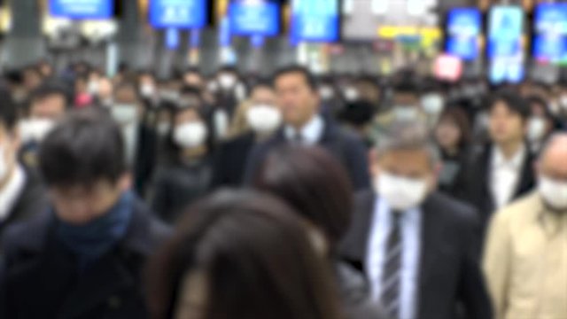 TOKYO, JAPAN - MARCH 2020 : Crowd of people walking at Shinagawa station in morning rush hour. Many commuters going to work. People wearing mask to protect from Coronavirus(COVID-19). Blurred shot.