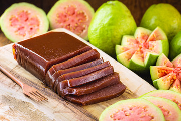 guava jam, called "goiabada cascão" in Brazil, with fruits in the background. Homemade dessert on wooden background in the background.