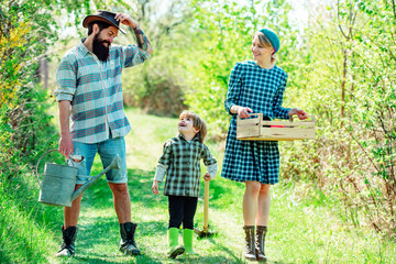 Family working together on farm. Farming gardening and family concept. Happy family: mother father and child son on spring field background.