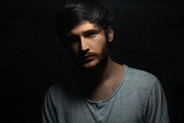 Dramatic dark portrait of young man on black background.