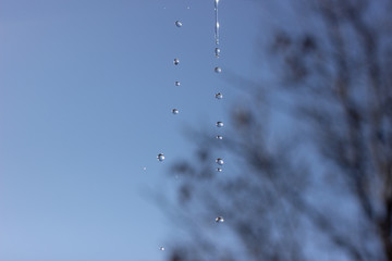Close-up macro of a water drop droplet - isolated over white background. Dripping water drops. Water drops against the blue sky