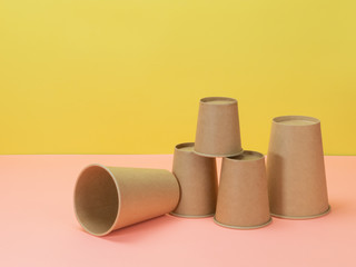 Eco-friendly paper cups in pink and yellow background.
