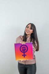 Brunette activist girl, wearing a pink jacket and white background with a feminine power poster, showing it to the public.