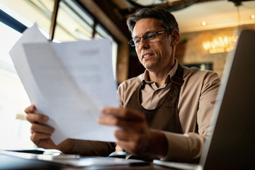 Obraz premium Below view of of happy cafe owner going through paperwork.
