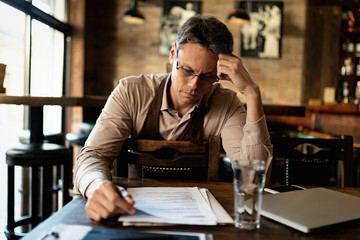 Bar owner reading reports and going through paperwork after working hours.