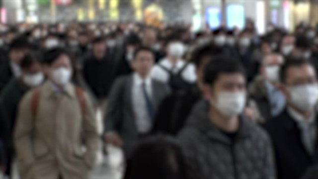 TOKYO, JAPAN - MARCH 2020 : Crowd of people walking at Shinagawa station in morning rush hour. Many commuters going to work. People wearing mask to protect from Coronavirus(COVID-19). Blurred shot.