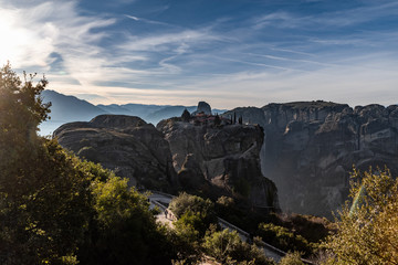 Aerial view of monastery Trinity and breathtaking pictures of valley and landmark canyon of Meteora at sunset, Kalambaka, Greece, shadows, twisted road, bridge, Mountains as columns