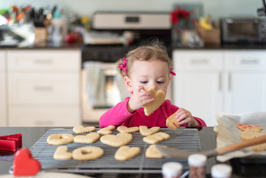 Toddler girl helping make heart shaped sugar cookies