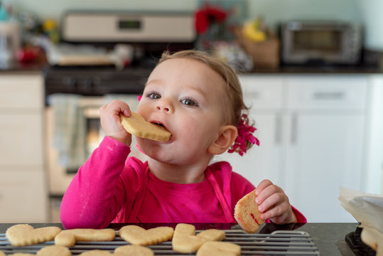 Closeup of little girl taking a bite out of a heart shaped sugar cookie