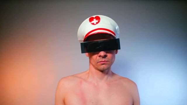 A man without a T-shirt in black glasses appears in the frame, looks around and hides down. The concept of an unexpected meeting.