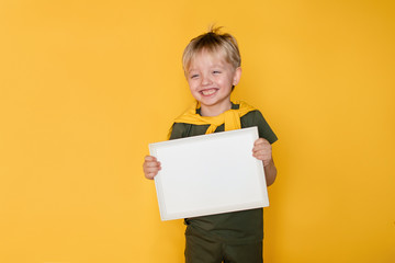 Happy cute boy child holding a blank sheet of paper. Yellow background. © Юлия Призова
