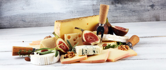 Cheese plate served with figs, various cheese on a rustic table