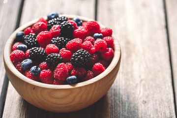 raspberries and blackberries on a wooden background in vintage style. Cutting board