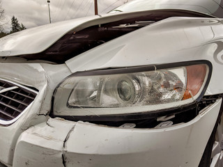 damage to the front bumper and headlight of a white car