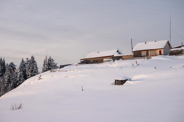 Winter landscape. Exterior view of wooden houses covered with snow in Russian village located in Siberia. Russia.