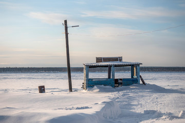 Empty pier on the bank of the frozen Yenisei river in Siberia with scenic pine winter forest in the background. Russia.