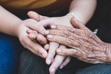 Young grandchildren's holding older grandmother hands feel with support together, wrinkled skin...