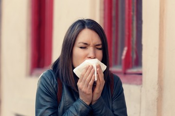 Ill woman with flu virus caughing sneezing in handkerchief  outdoors 