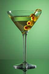 Glass of Martini with olives. Extra dry vermouth martini. Alcohol cocktail on green background. 