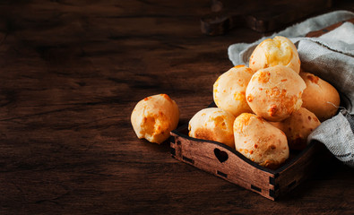 Cheese buns in wooden bowl, rustic kitchen table background, copy space, selective focus