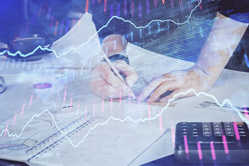 Double exposure of man writing on paper with forex graph.
