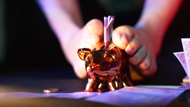 Artistic setting. Close-up of Dominatrix legs stroking a golden piggy bank. The concept of dominatrix and female energy.