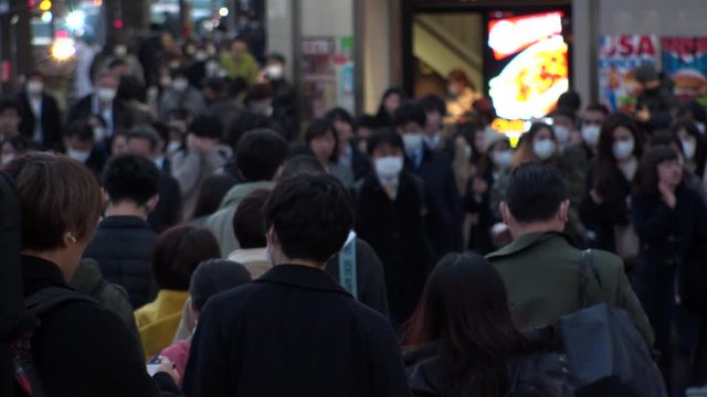 TOKYO, JAPAN - MARCH 2020 : Crowd of people at the street near Shinjuku station in rush hour. Commuters and tourists wearing surgical mask to protect from Coronavirus(COVID-19) or cold. Slow motion.