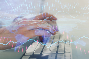 Double exposure of graph with man typing on computer in office on background. Concept of hard work....