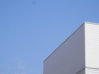 Fototapeta na wymiar 白い壁の建物上部と青空