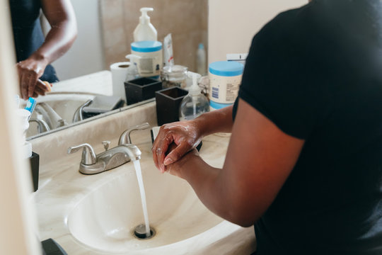 Black Woman Washing Hands in Sink