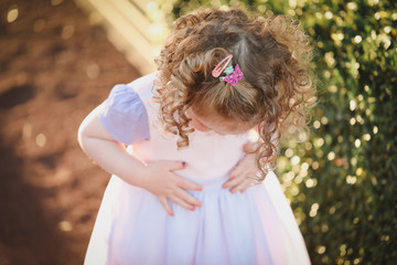 Naklejka premium Portrait of little girl spinning in pretty dress bathed in sunlight