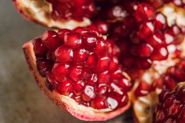Broken red ripe pomegranate fruit on the dark rustic background. Selective focus. Shallow depth of field.