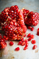 Broken red ripe pomegranate fruit on the dark rustic background. Selective focus. Shallow depth of field.