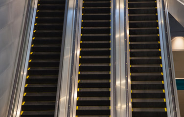 Escalators in subway train station towards upper levels, used in places where lifts would be impractical. Transportation between floors or levels in subways, buildings, and other mass pedestrian areas