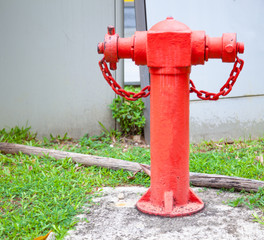 Red Asian Vintage above-ground pillar-type Fire Hydrant at a street corner with building...
