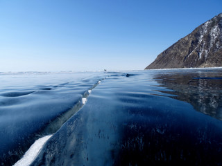 the dark blue surface of the ice is crossed by a crack extending to the horizon