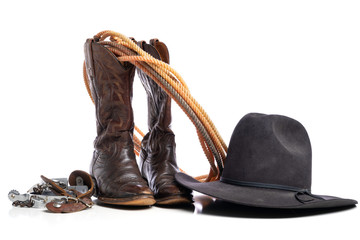 Western boots and a lap or lariat rope and spurs and a cowboy hat on a white background