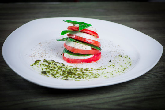 Ensalada Capressa Tomate queso albahaca y pesto en plato blanco