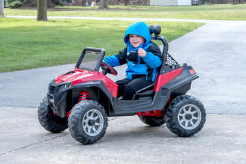 a cute little boy poses as he drives a battery powered jeep