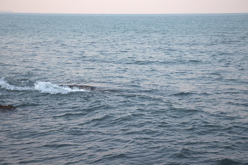 Obraz premium Waves breaking over a rocky outcrop creating a whirlpool and waterfall effect