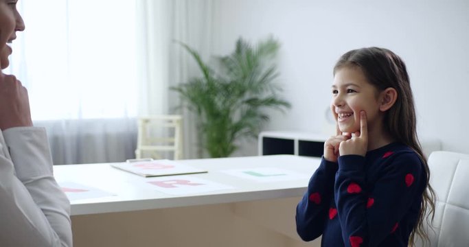Speech therapist working with little girl in office