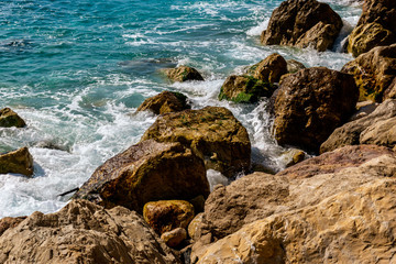 Fototapeta na wymiar A close-up shot of the Mediterranean Sea turquoise water and powerful waves beating against the rocks on the coast