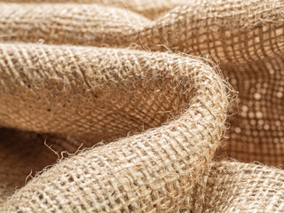Crumpled sackcloth, close up view, abstract background. Texture of brown burlap textile. Brown baline. Selective soft focus. Blurred background