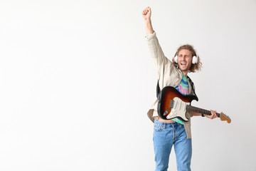 Emotional man playing guitar on light background