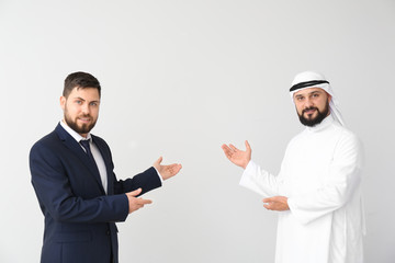 Arab man and his business partner showing something on grey background